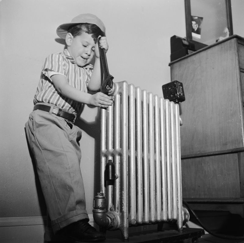 Young boy witha cast iron radiator around the 1930's